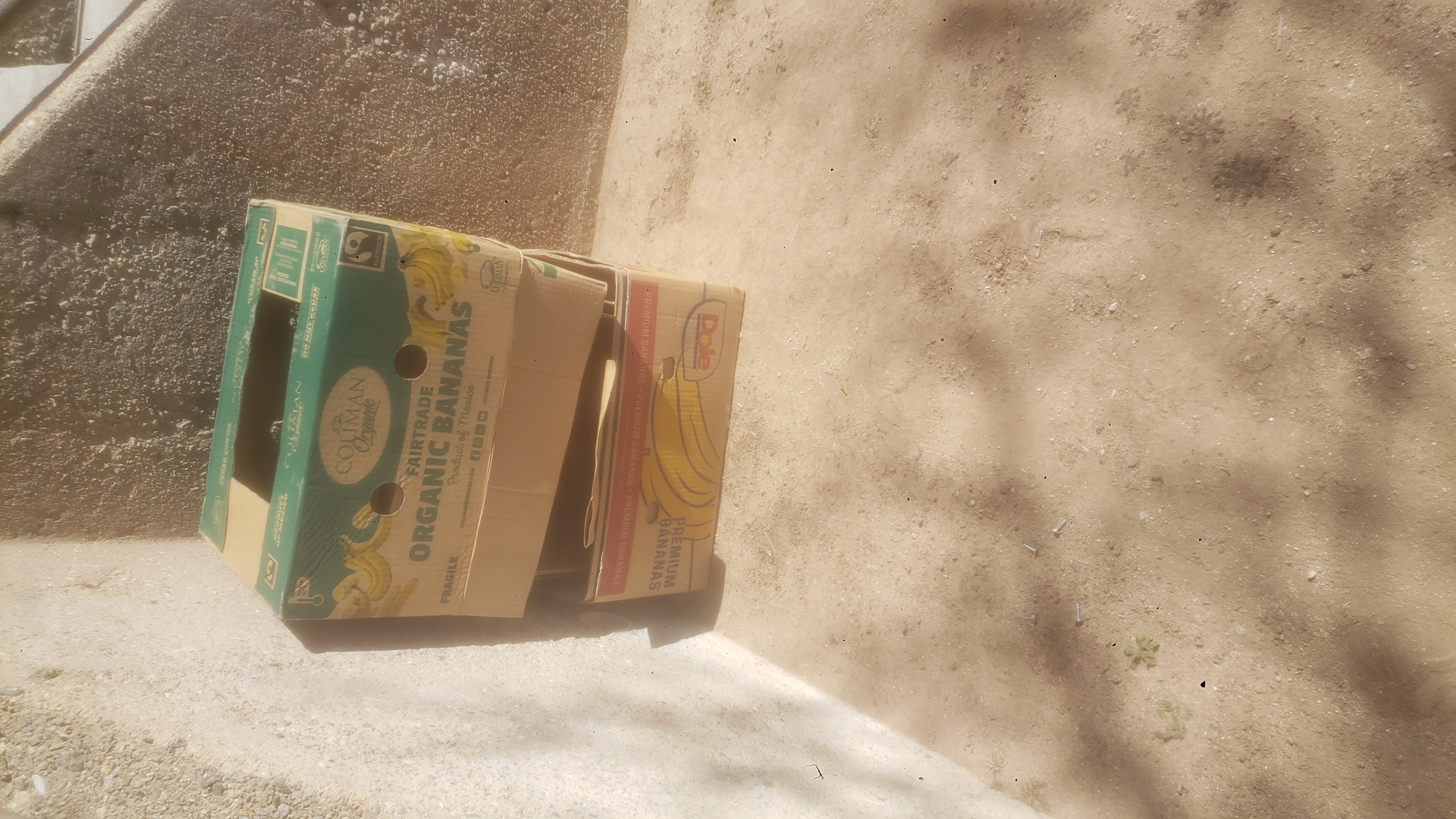 Two banana box stacked on each other on concrete sidewalk.